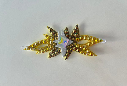 Añade un toque especial al peinado con esta corona decorativa para moño de gimnasia rítmica. Diseñada para rodear el moño de forma armoniosa, aporta un acabado elegante y sofisticado que realza la presencia de la gimnasta en tapiz.